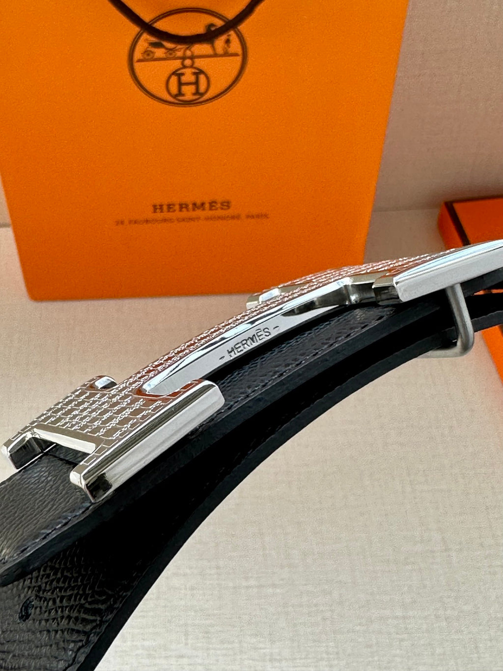 Silver-tone buckle detail on black leather belt with keeper
