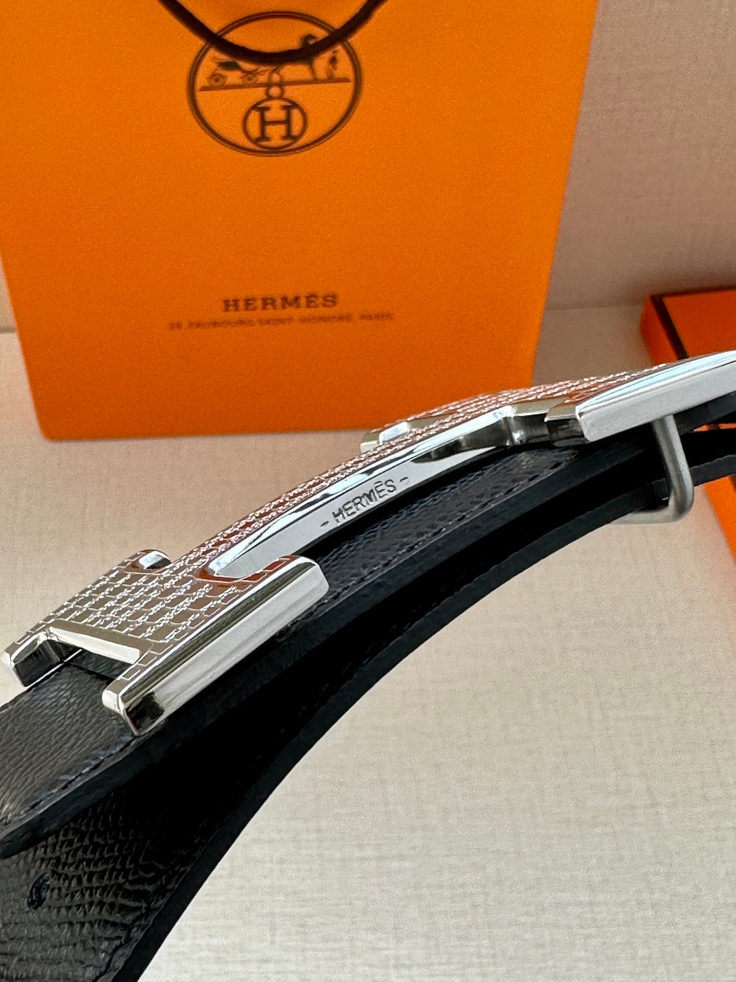 Silver-tone buckle detail on black leather belt with keeper