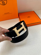 Black leather belt with large silver-tone buckle, held close-up