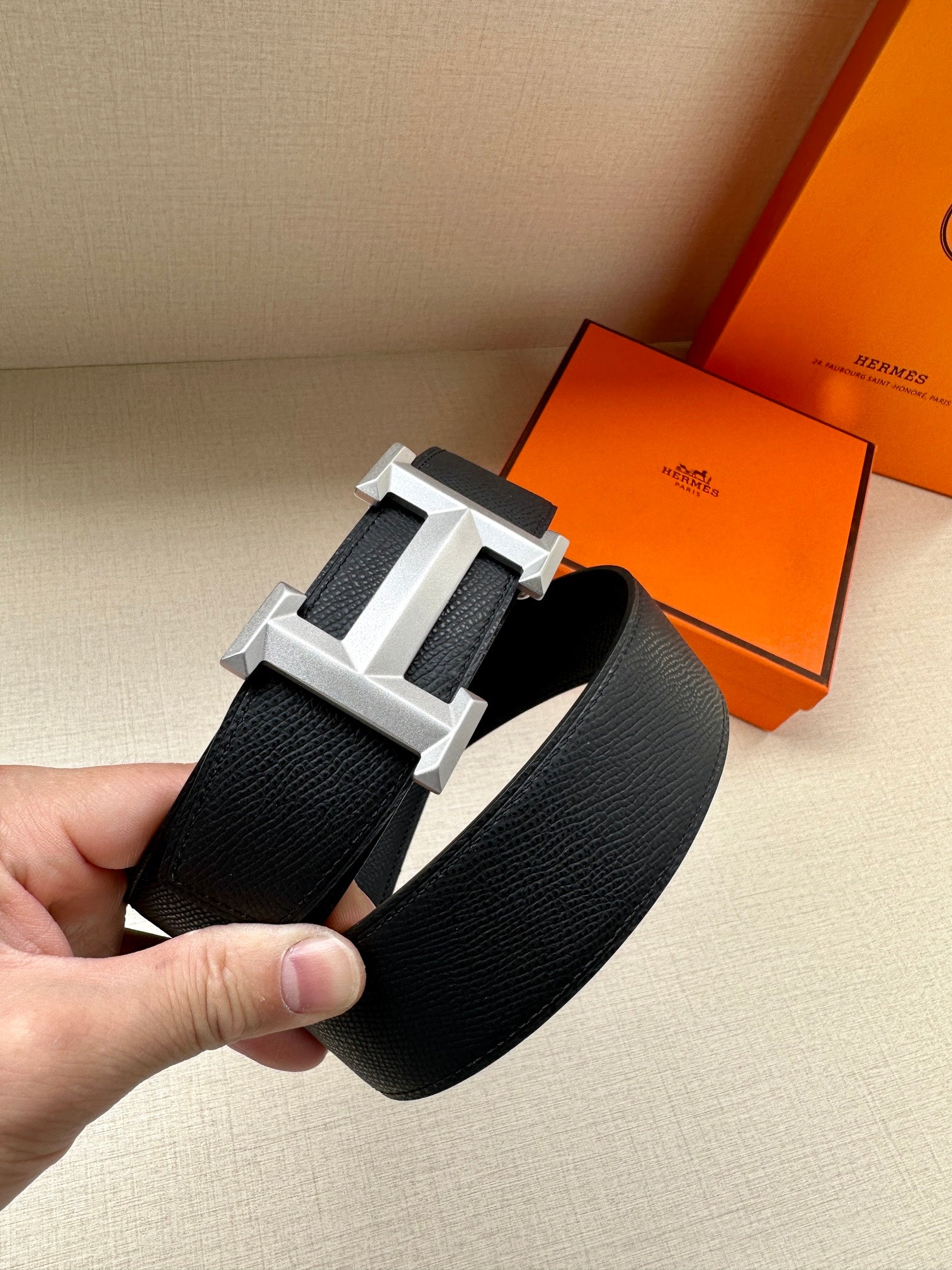 Hermes belt in dark textured leather with silver-toned geometric buckle.
