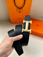 Hermes dark leather belt with textured finish and gold-toned rectangular buckle.