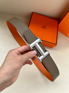 Leather belt with textured dark gray strap and silver-tone H buckle.