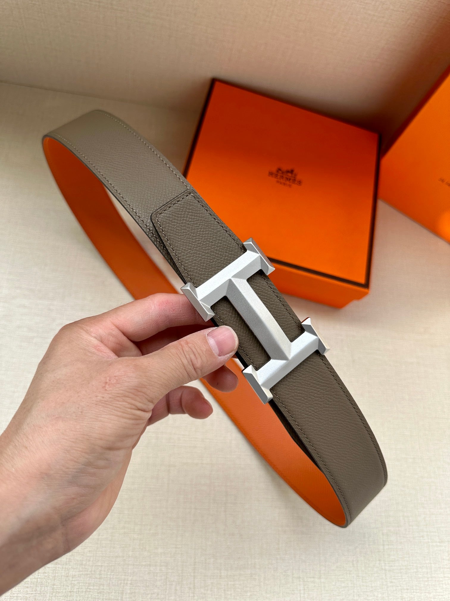 Leather belt with textured dark gray strap and silver-tone H buckle.