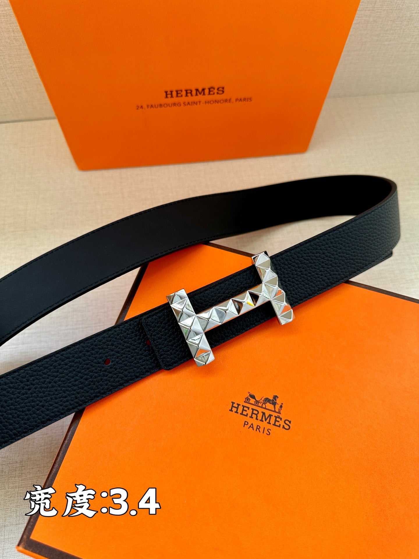 Black leather belt with silver-tone studded buckle and dark strap holes.