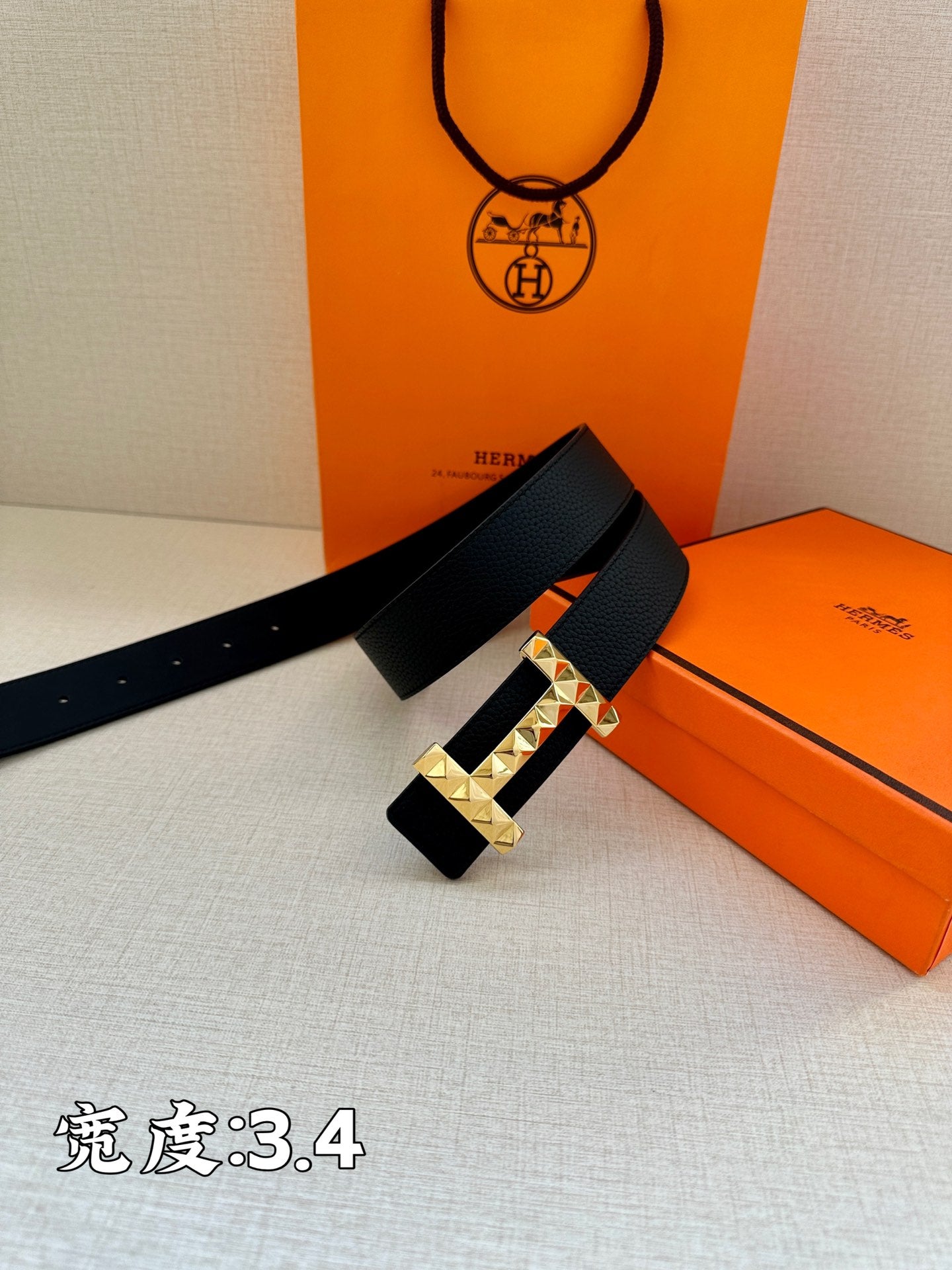 Black leather belt with silver-tone studded buckle resting on tabletop.