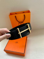Black leather belt with gold rectangular buckle, smooth side visible