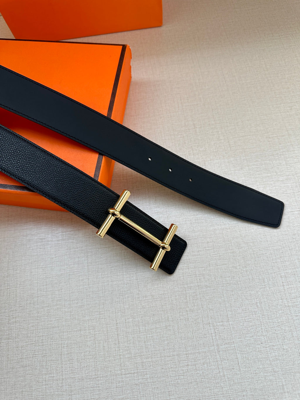 Black leather belt with gold buckle frame and two strap holes