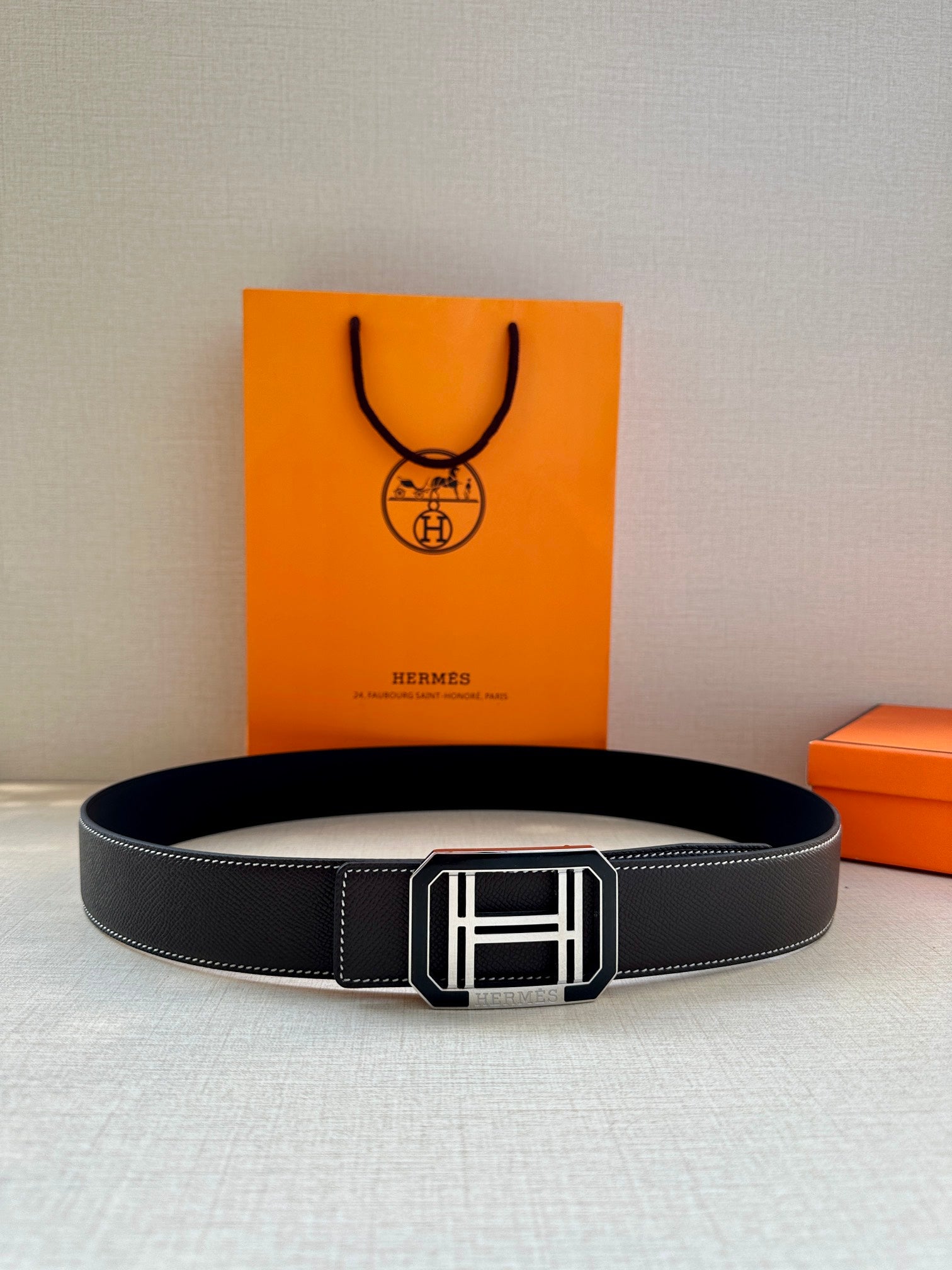 Black leather belt laid flat with silver-tone rectangular buckle
