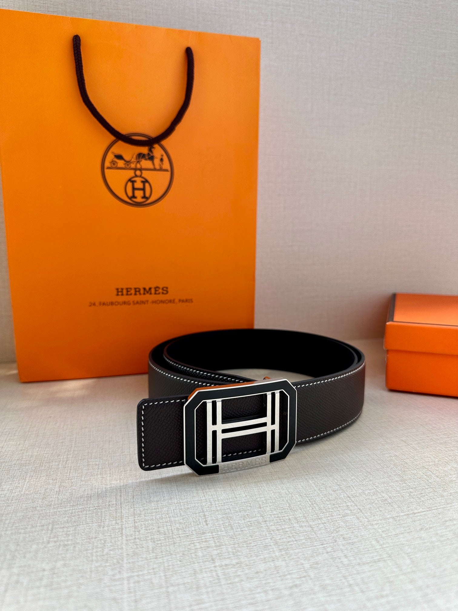 Black leather belt with silver-tone rectangular buckle and stitched keeper