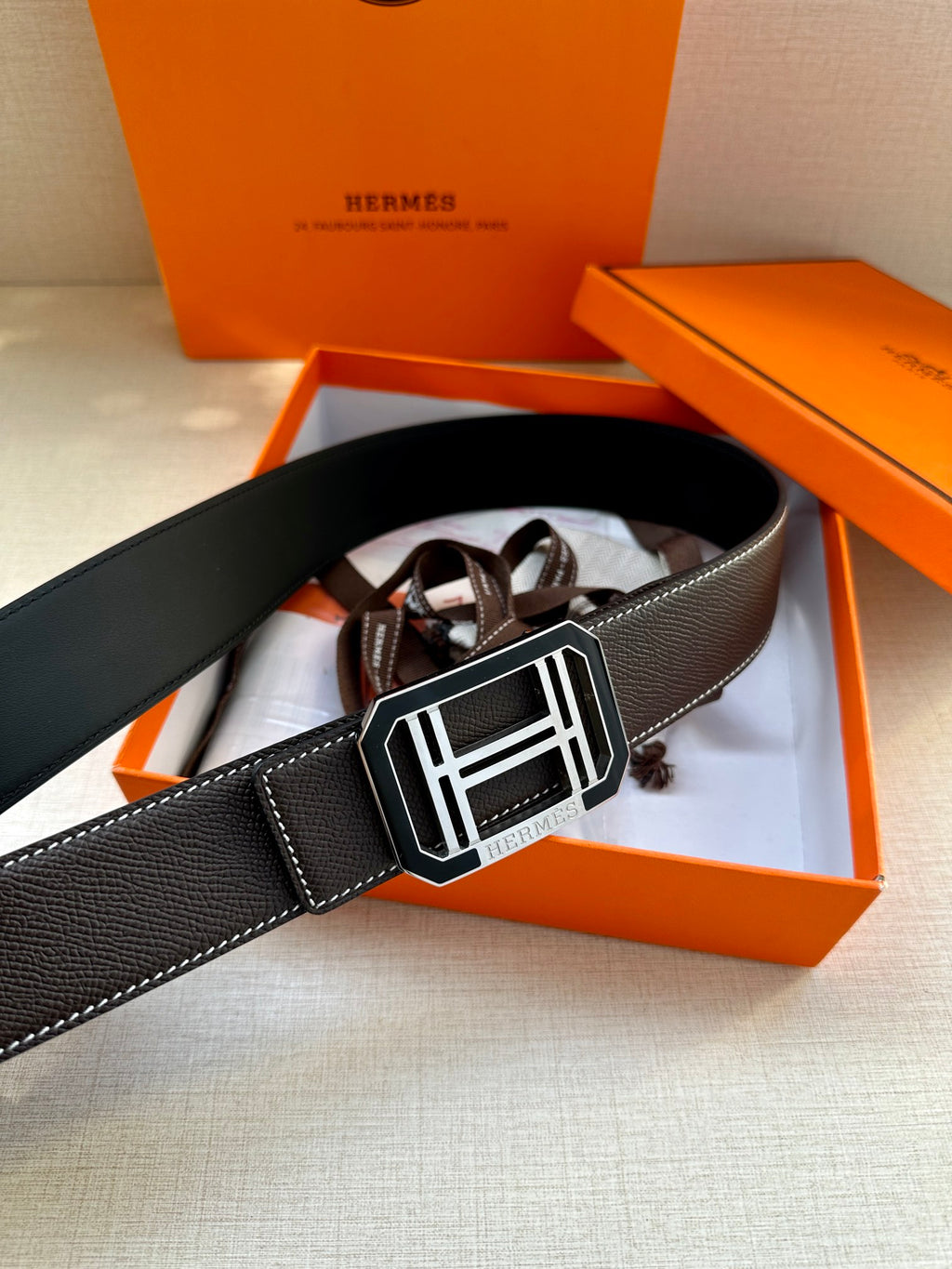 Black leather belt featuring a large silver-tone rectangular buckle
