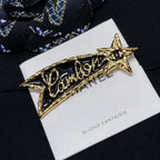 Gold-tone Chanel logo brooch with star ends on Bijoux Fantaisie card