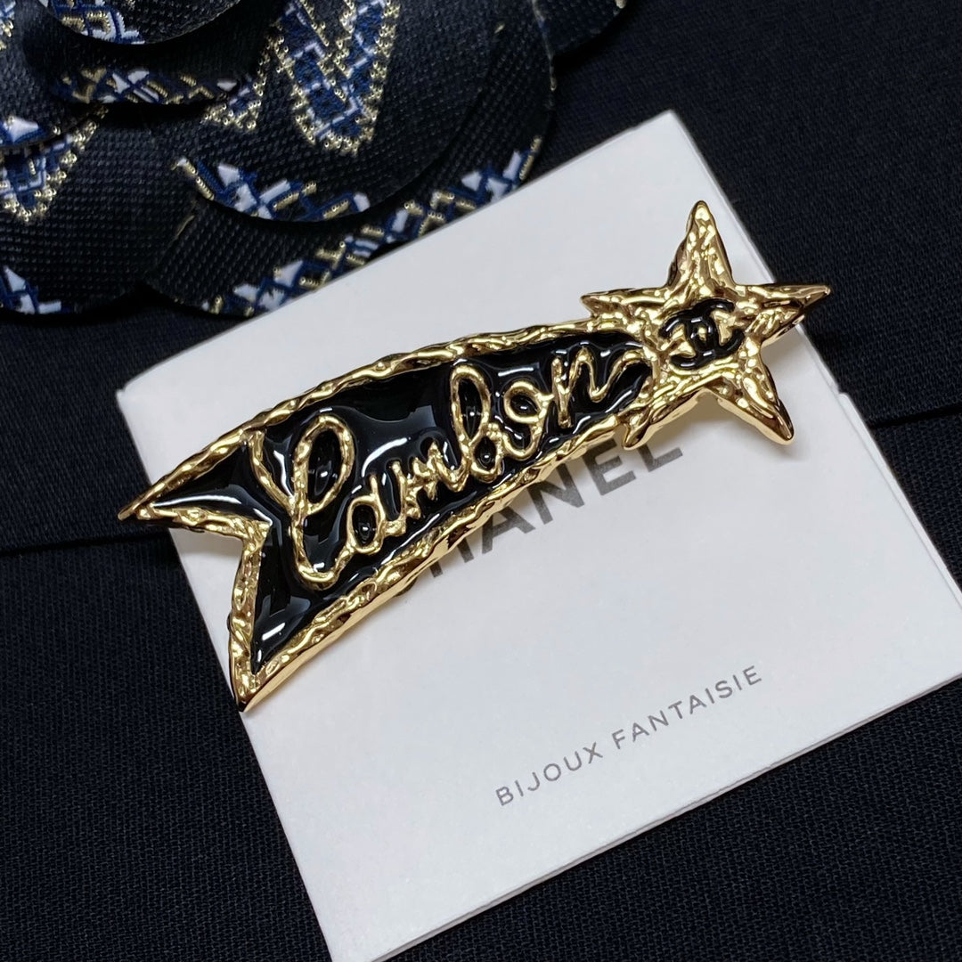 Gold-tone Chanel logo brooch with star ends on Bijoux Fantaisie card