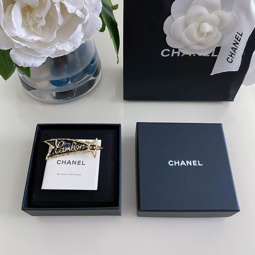 Chanel gift boxes with black insert and gold-tone logo brooch on white card
