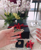 Chanel logo patch on black gift bag held in hands, gold-tone brooch visible