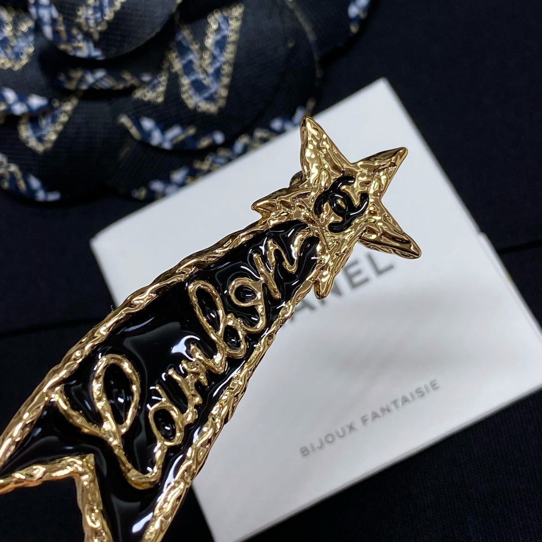 Close-up gold-tone Chanel logo brooch with star top on Bijoux Fantaisie card
