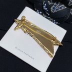 Gold-tone abstract bar brooch with star ends on Bijoux Fantaisie card