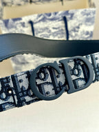 Dior belt close-up: dark oval buckle on black-and-blue monogram strap