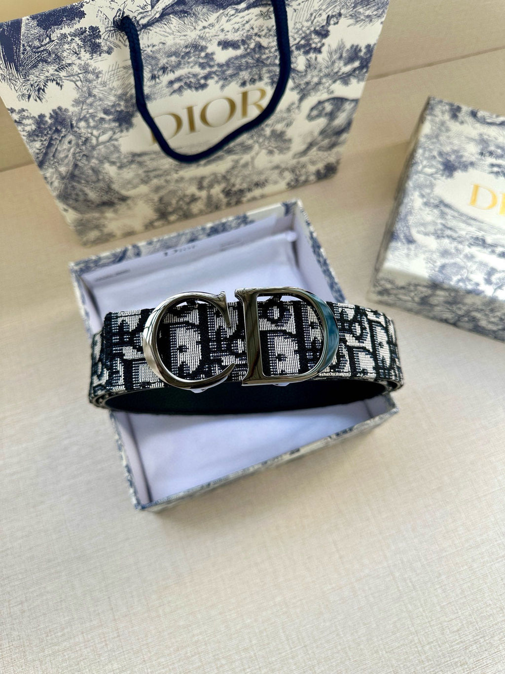 Dior belt on open box, blue logo-print strap with oval metal buckle