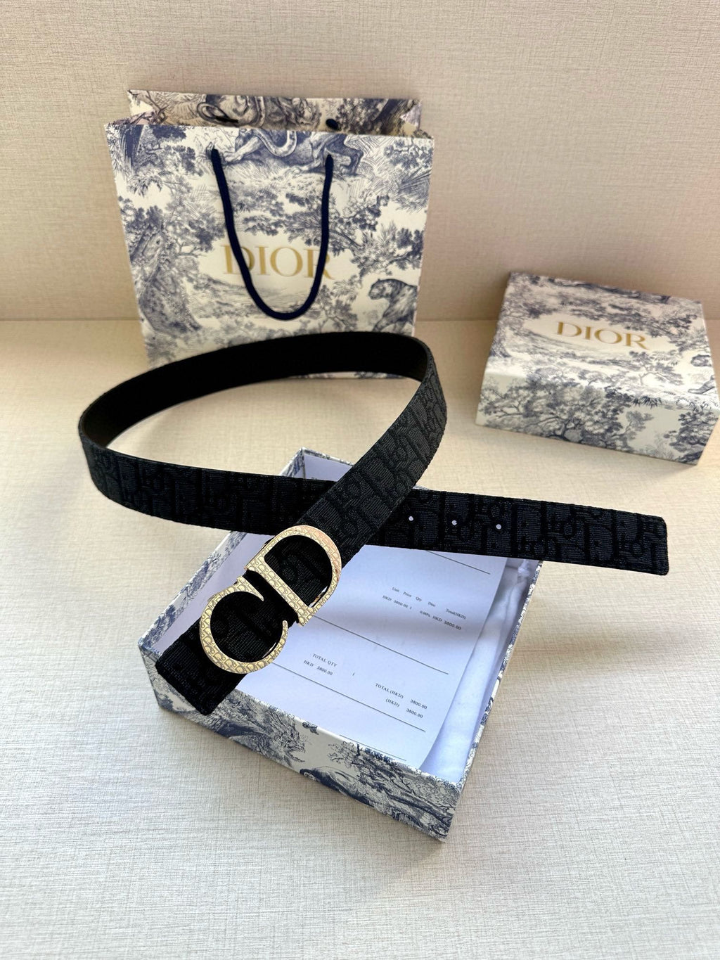 Dior belt with dark strap and gold CD buckle, shown on packaging
