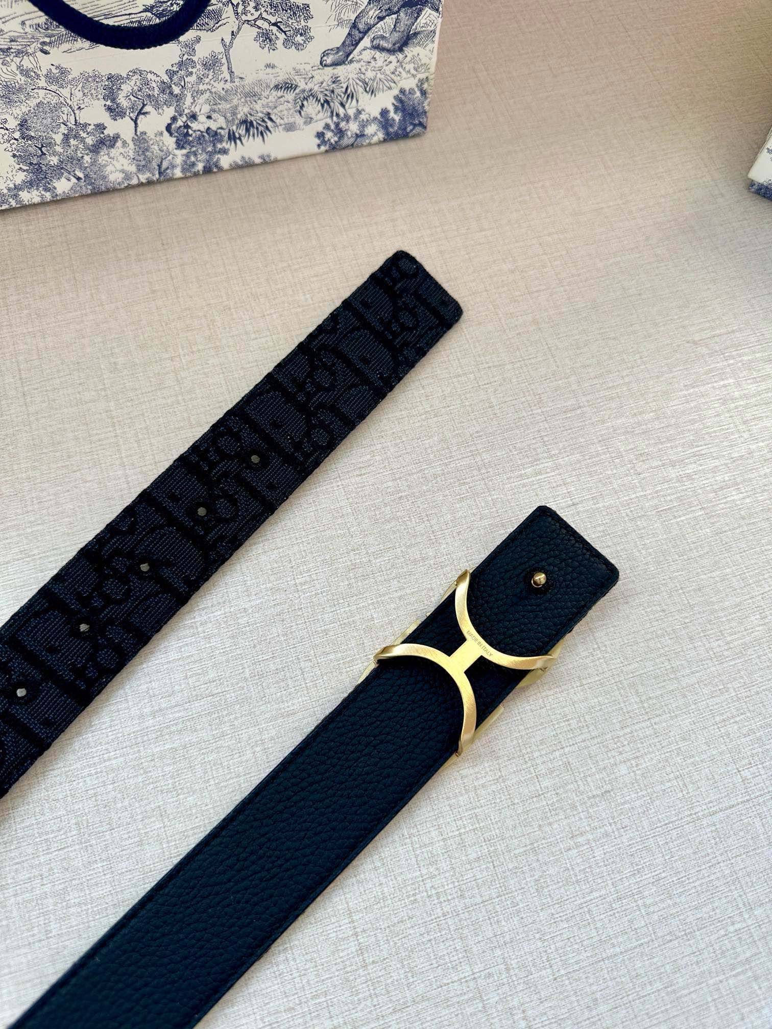 Navy belt with CD gold-tone buckle, studded holes and monogram print.