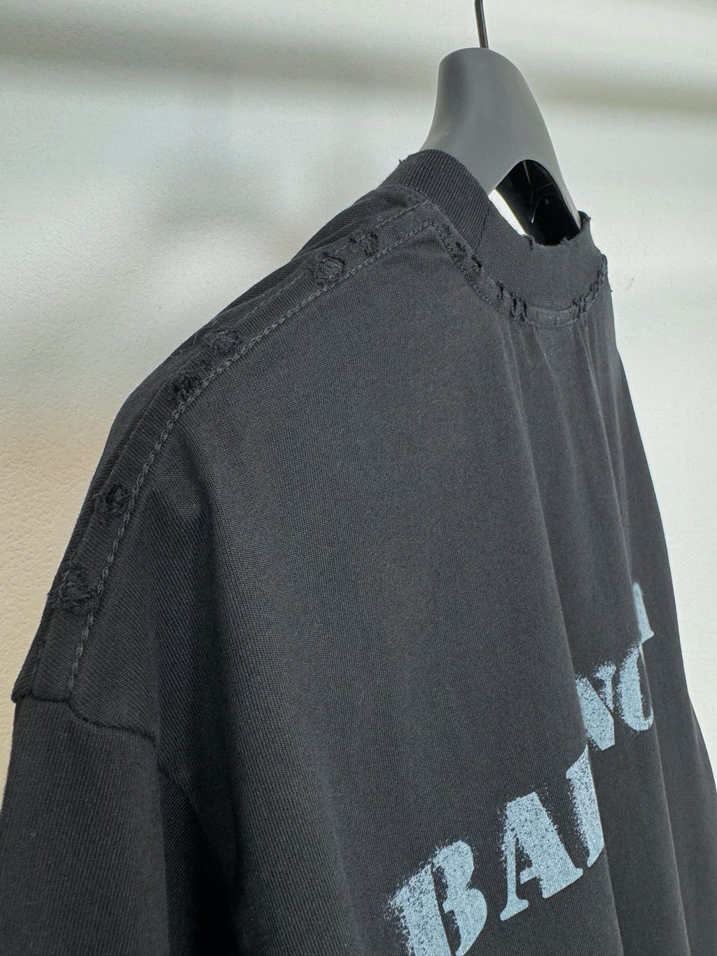 Dark Balenciaga T-shirt side view on hanger, stitched neckline and sleeve edge