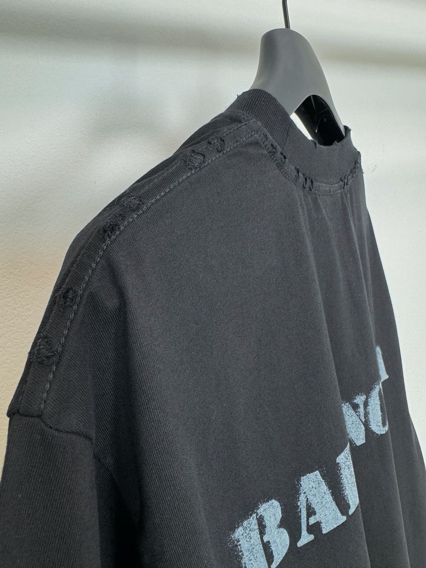 Dark Balenciaga T-shirt side view on hanger, stitched neckline and sleeve edge