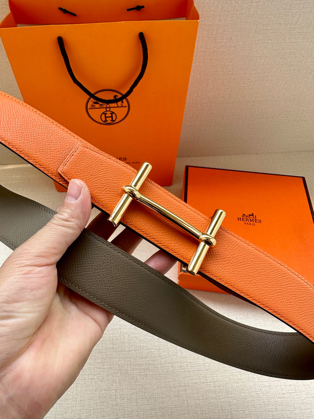 Hermes belt showing orange strap and dark underside with silver buckle