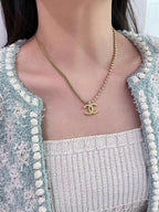 Gold-tone necklace with Chanel logo pendant, worn close to the neckline