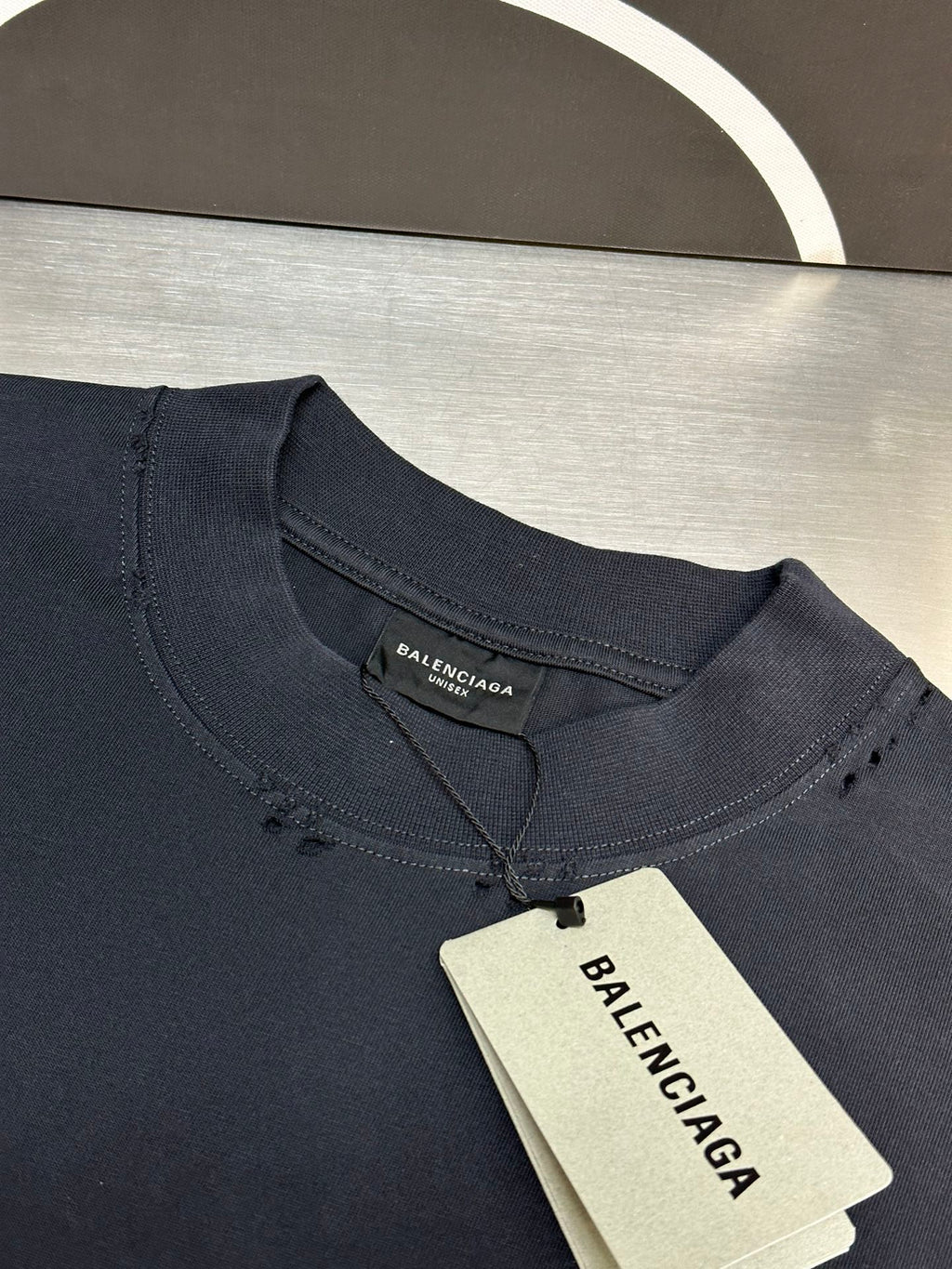 Dark blue crewneck T-shirt with inner neck label and hanging price tag.