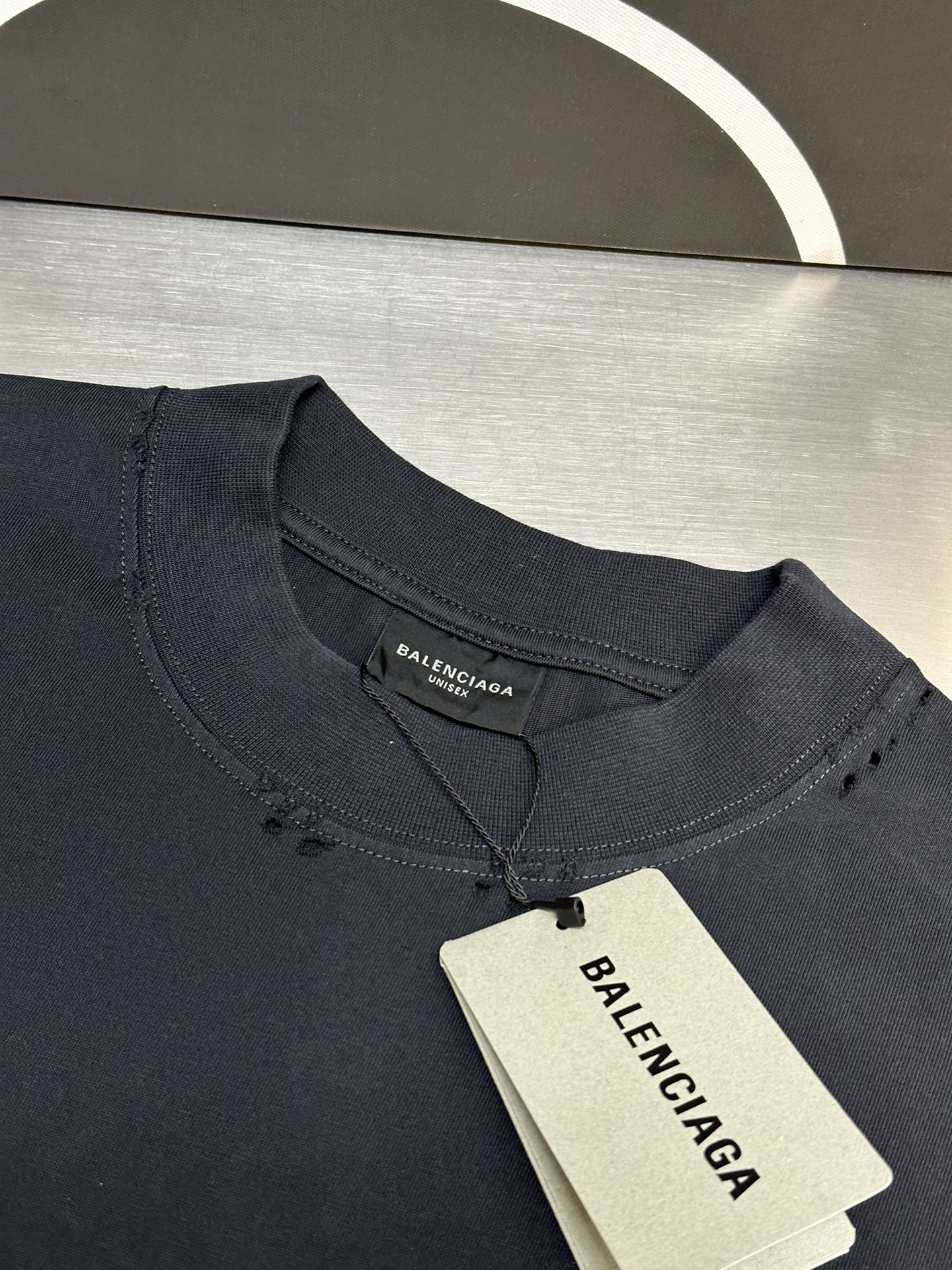Dark blue crewneck T-shirt with inner neck label and hanging price tag.