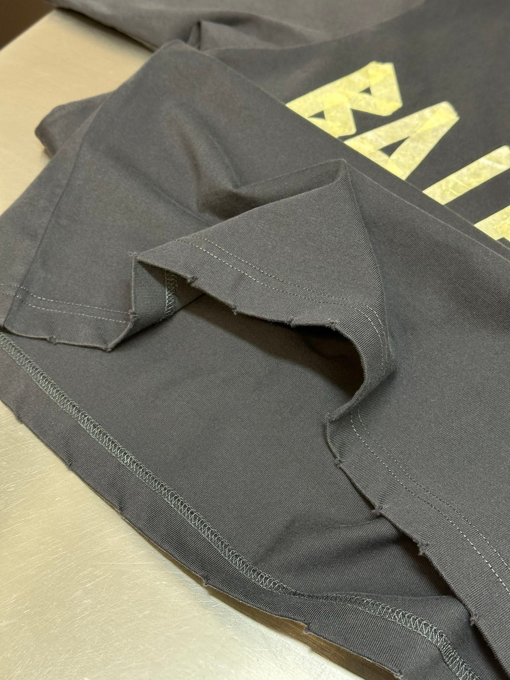 Folded dark blue T-shirt showing stitched hem and sleeve seam detail.