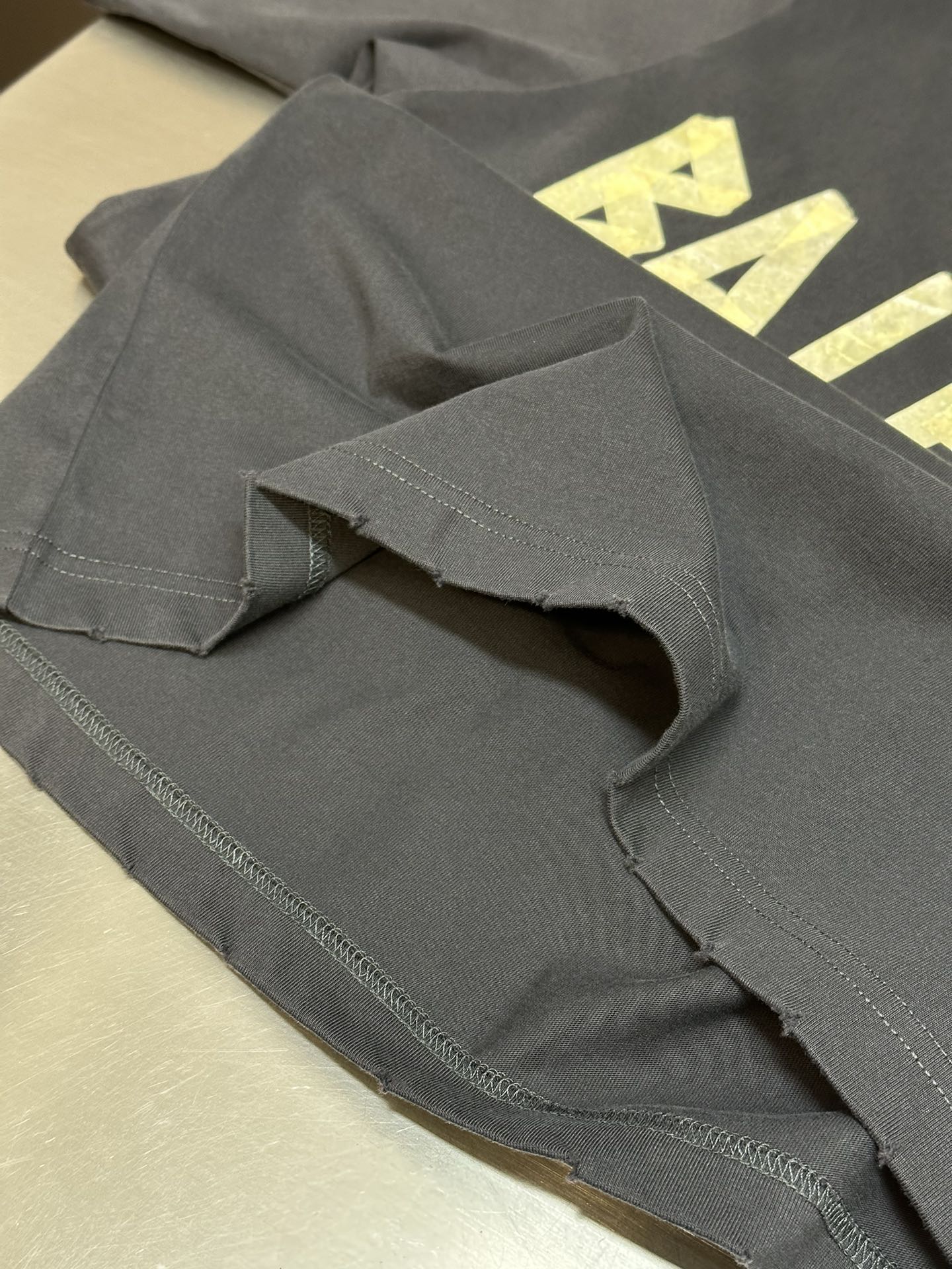 Folded dark blue T-shirt showing stitched hem and sleeve seam detail.