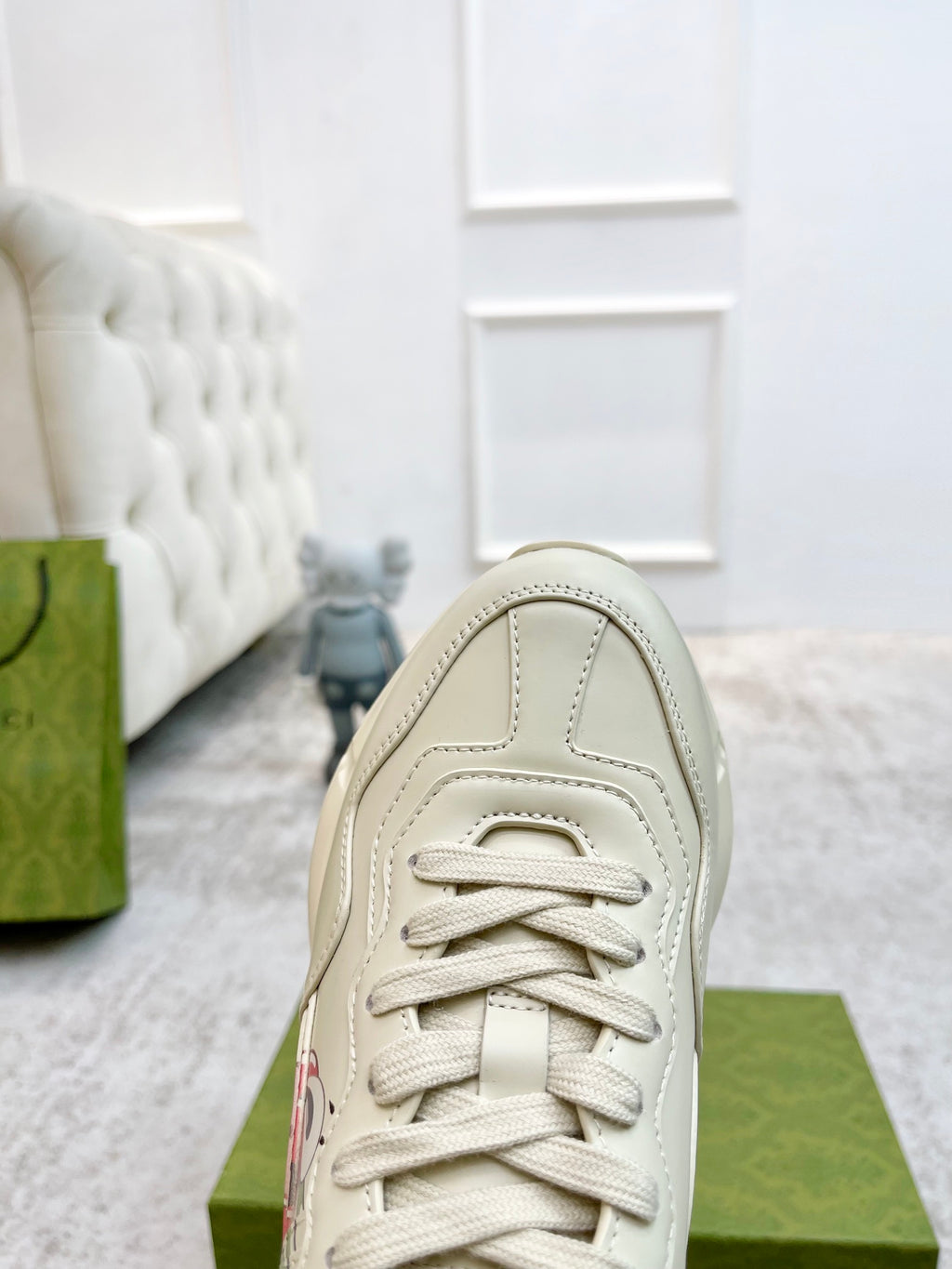 Unisex sneaker front in light color with lace-up closure and stitched panel details.