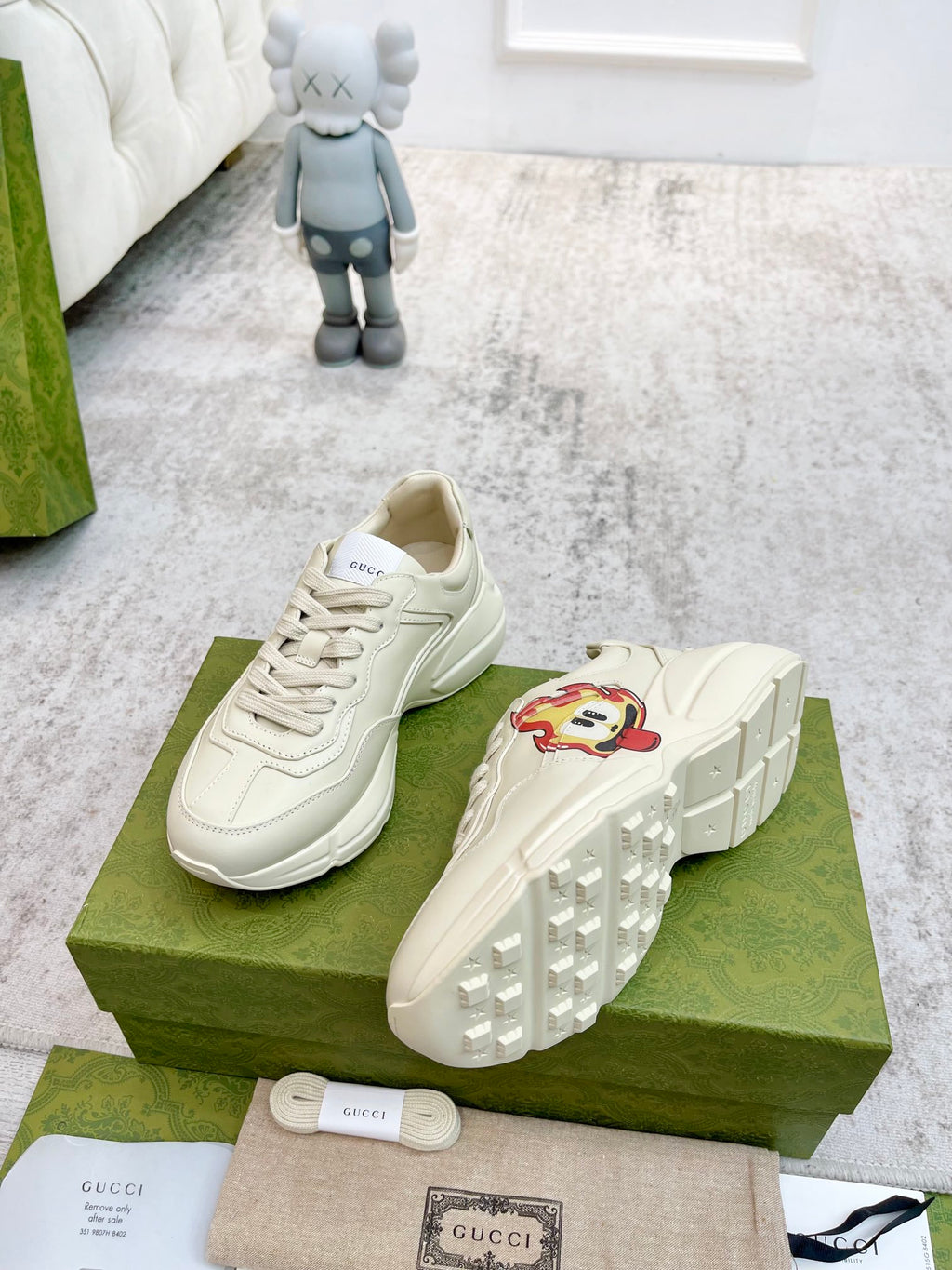 Cream Gucci lace-up sneakers with cartoon side patch; view of treaded outsole