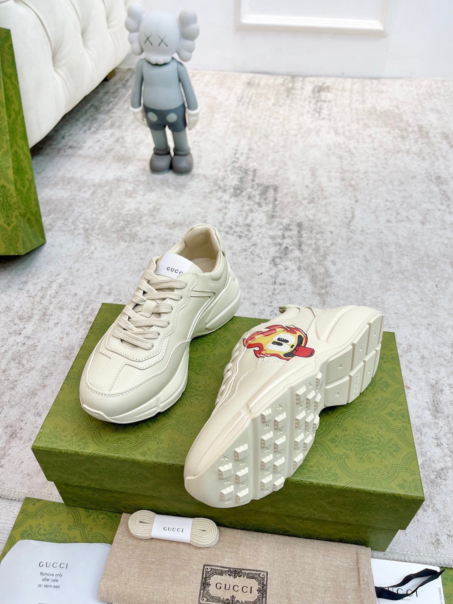 Cream Gucci lace-up sneakers with cartoon side patch; view of treaded outsole