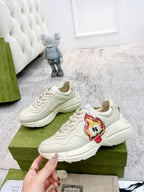 Cream lace-up sneakers with red cartoon patch on side; chunky sole and laces
