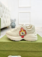 Cream lace-up sneakers with red cartoon face patch on side and thick sole