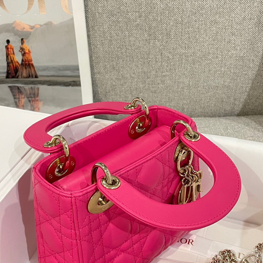 Pink quilted Dior handbag with top handle, gold hardware, and chain strap