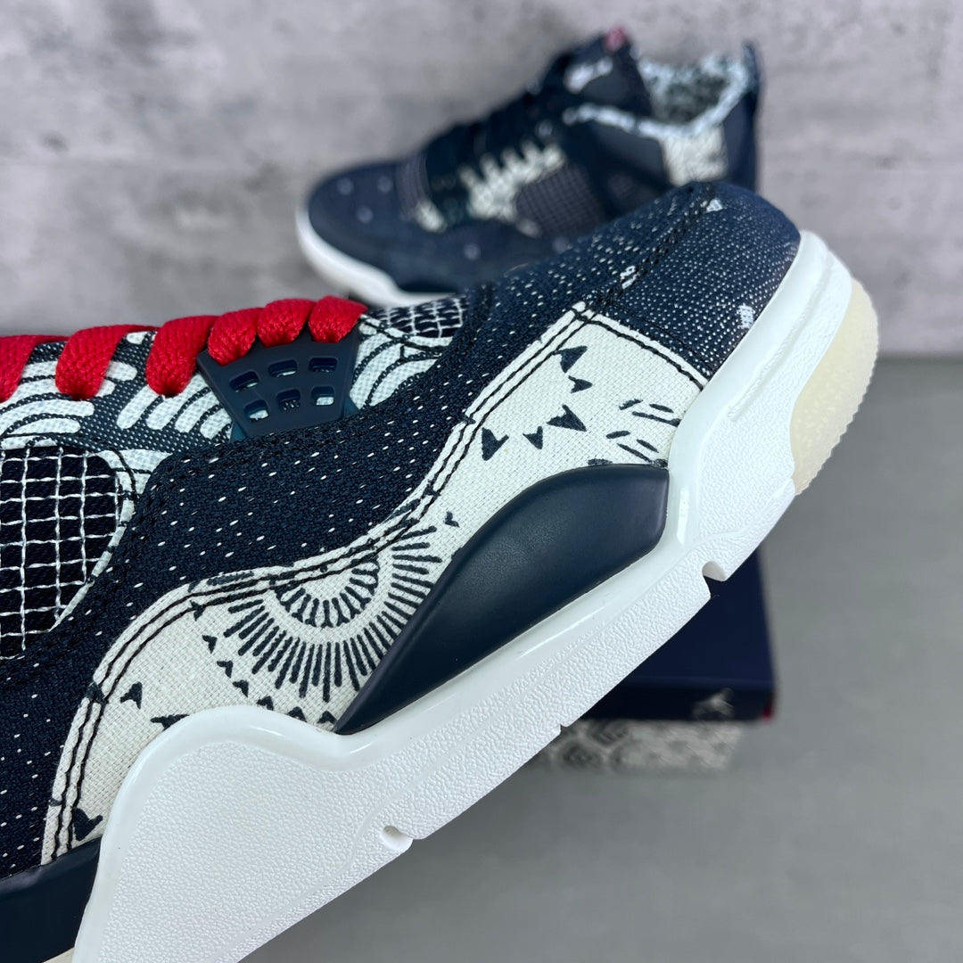 Navy sneaker close-up with red lace accents, white midsole, and stitched graphic panel