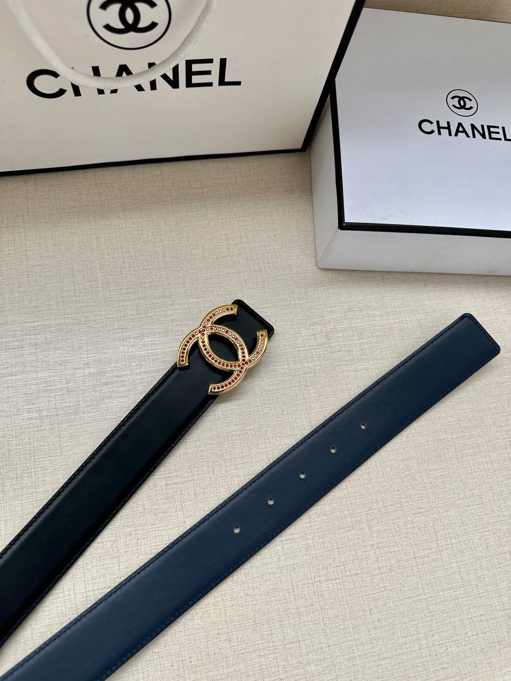 Dark leather Chanel belt with gold CC-style buckle and evenly spaced holes