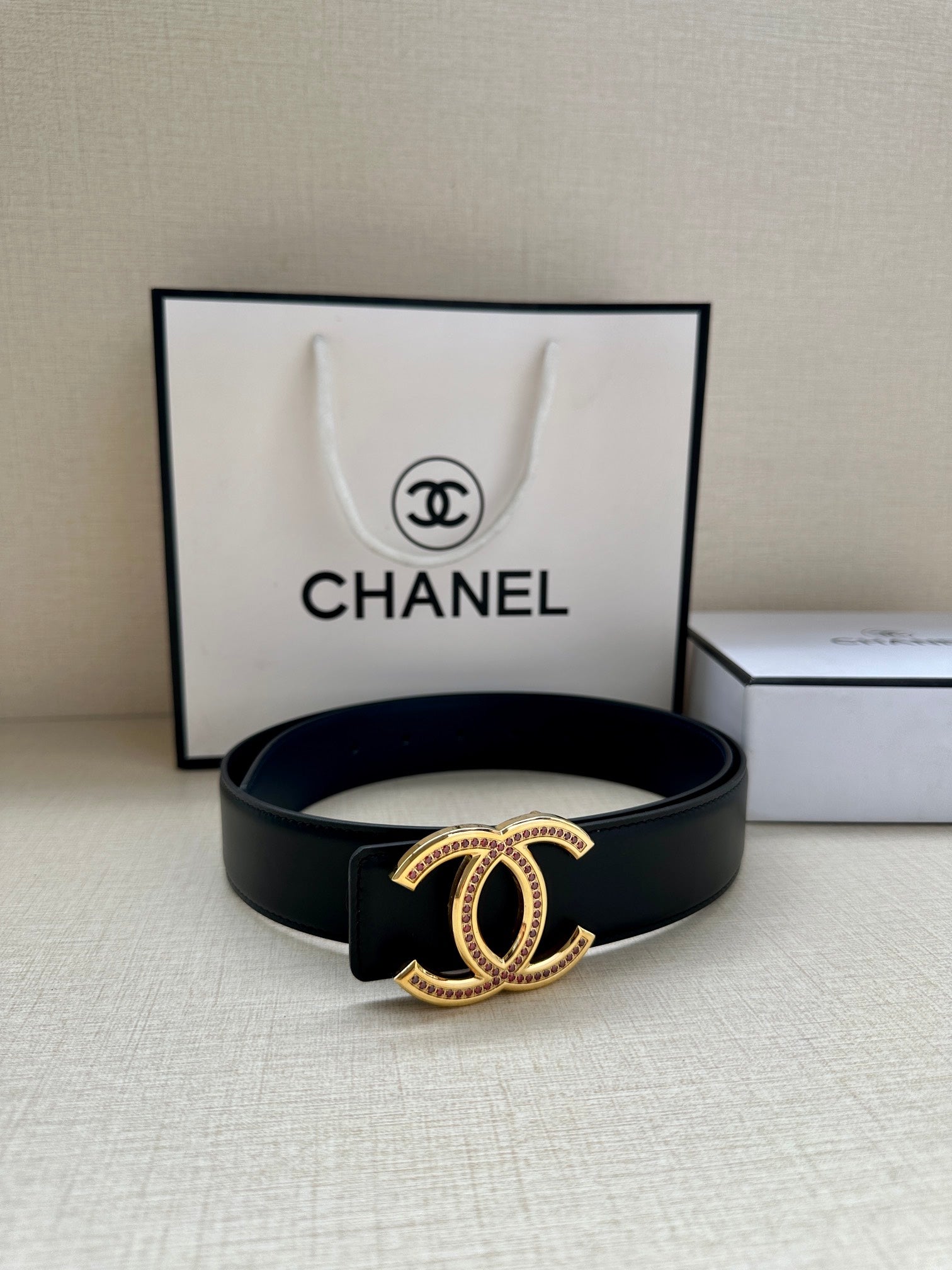 Dark leather Chanel belt with gold CC-style buckle featuring pink and clear stone detail