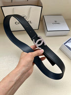 Dark leather belt looped in hand, showing CC-style buckle with stone inlays