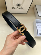 Dark leather belt with gold CC-style buckle and pink stone accents, held in hand