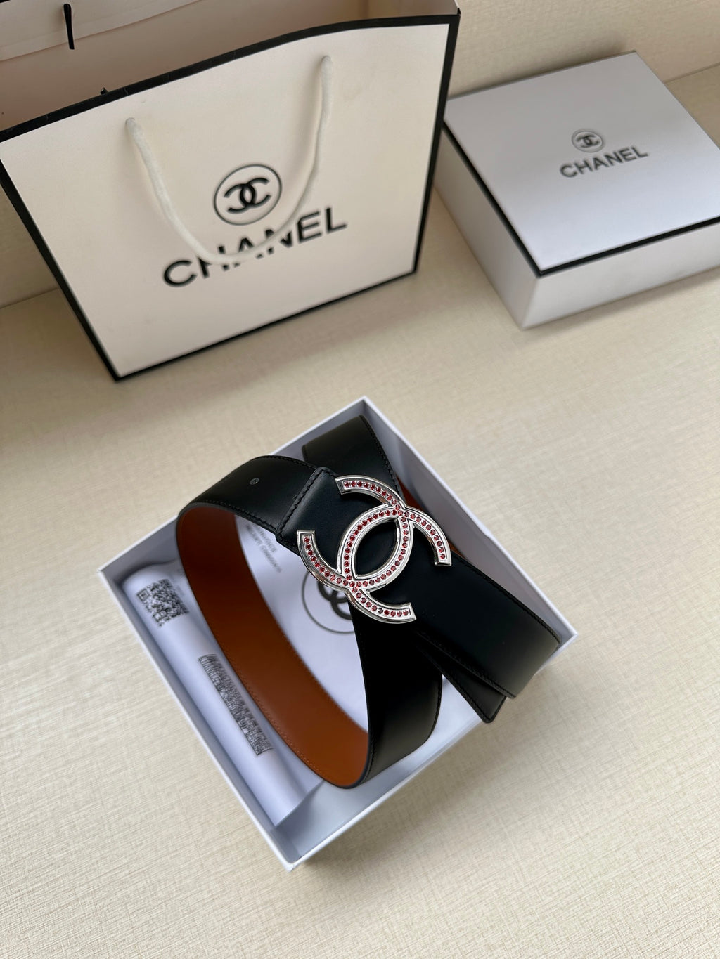 Black leather belt with gold-tone double-C buckle and jeweled trim.
