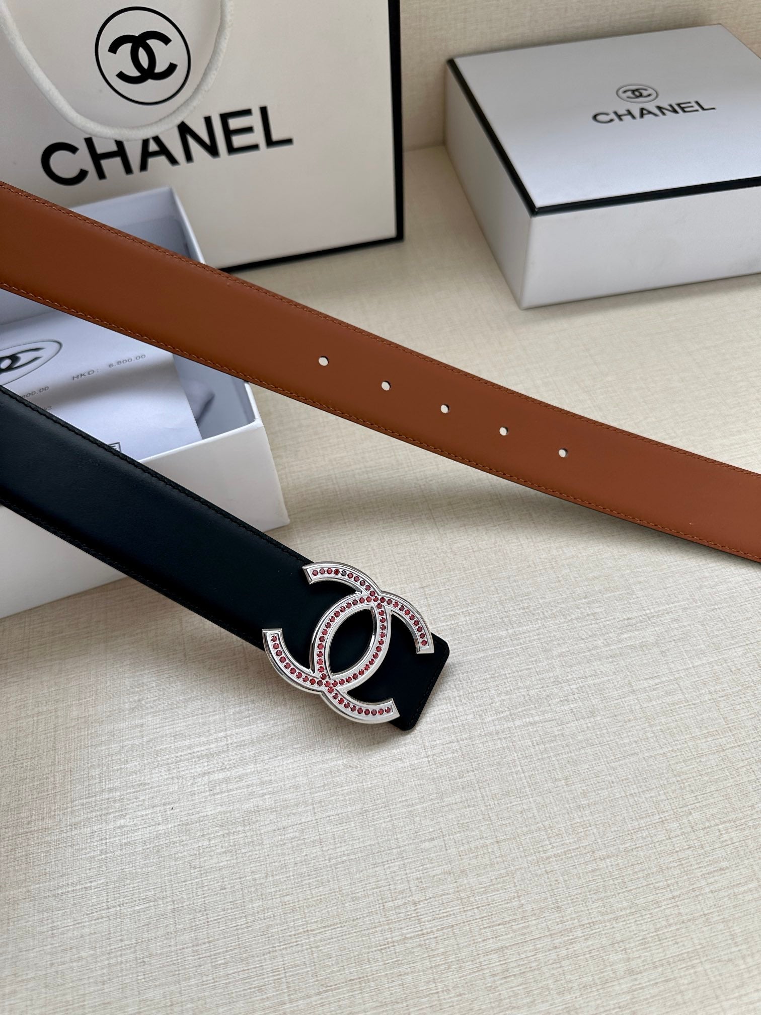 Brown and black leather belt straps with double-C buckle and jeweled insets.