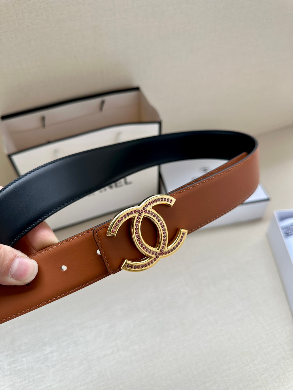 Brown leather belt with gold-tone double-C buckle detail on the strap.