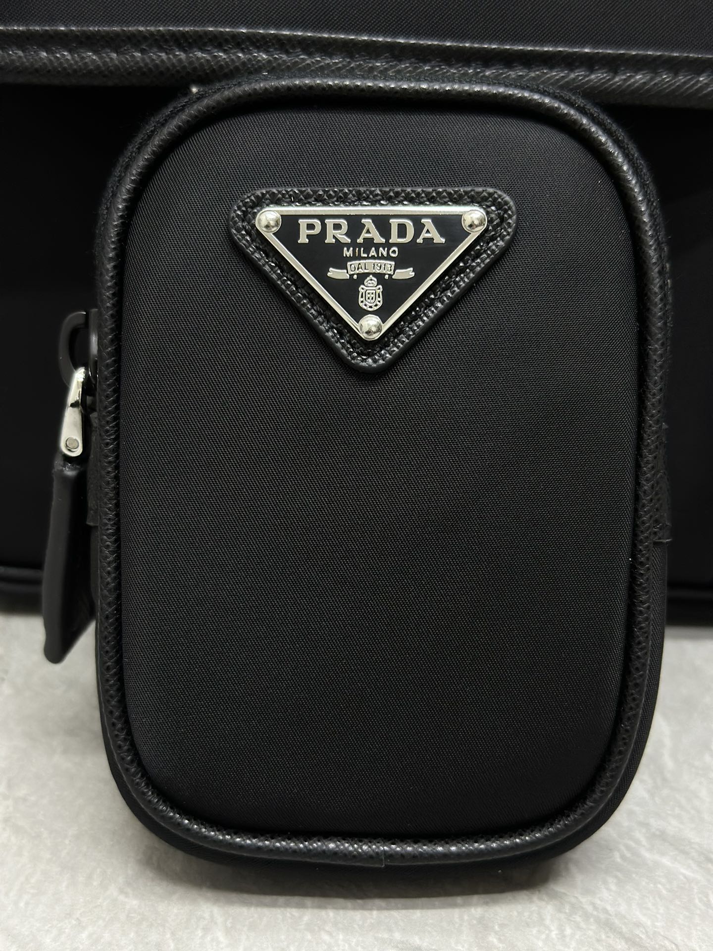Prada mini crossbody pouch with triangular logo plaque and zipper closure