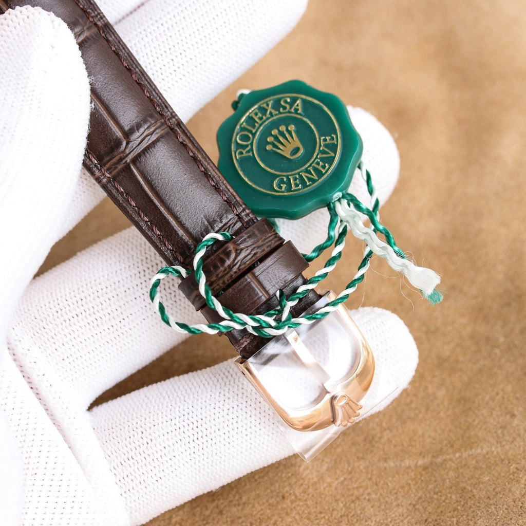 Cellini wristwatch clasp with green emblem and brown leather strap buckle