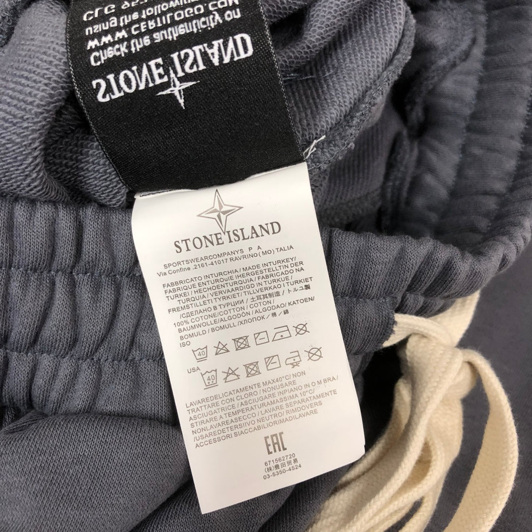 Stone Island shorts waistband with black size tag and care label on gray fabric