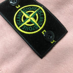Stone Island logo patch on pink shorts, yellow emblem on black label